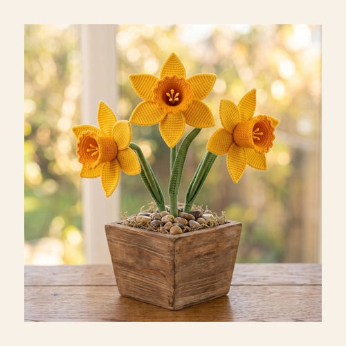 Crochet daffodil flower pot with yellow daffodils in a wooden planter