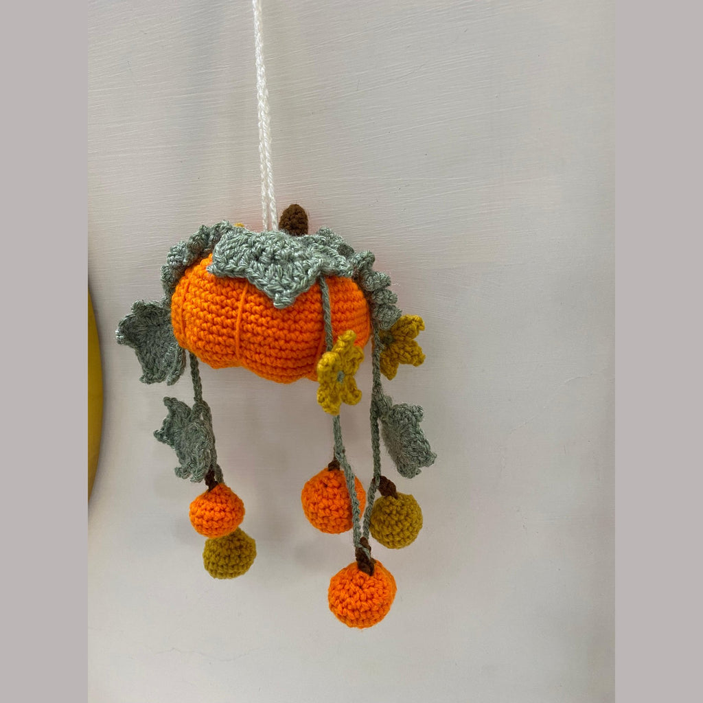 Crochet pumpkin hanging decoration with mustard flowers and curly vines