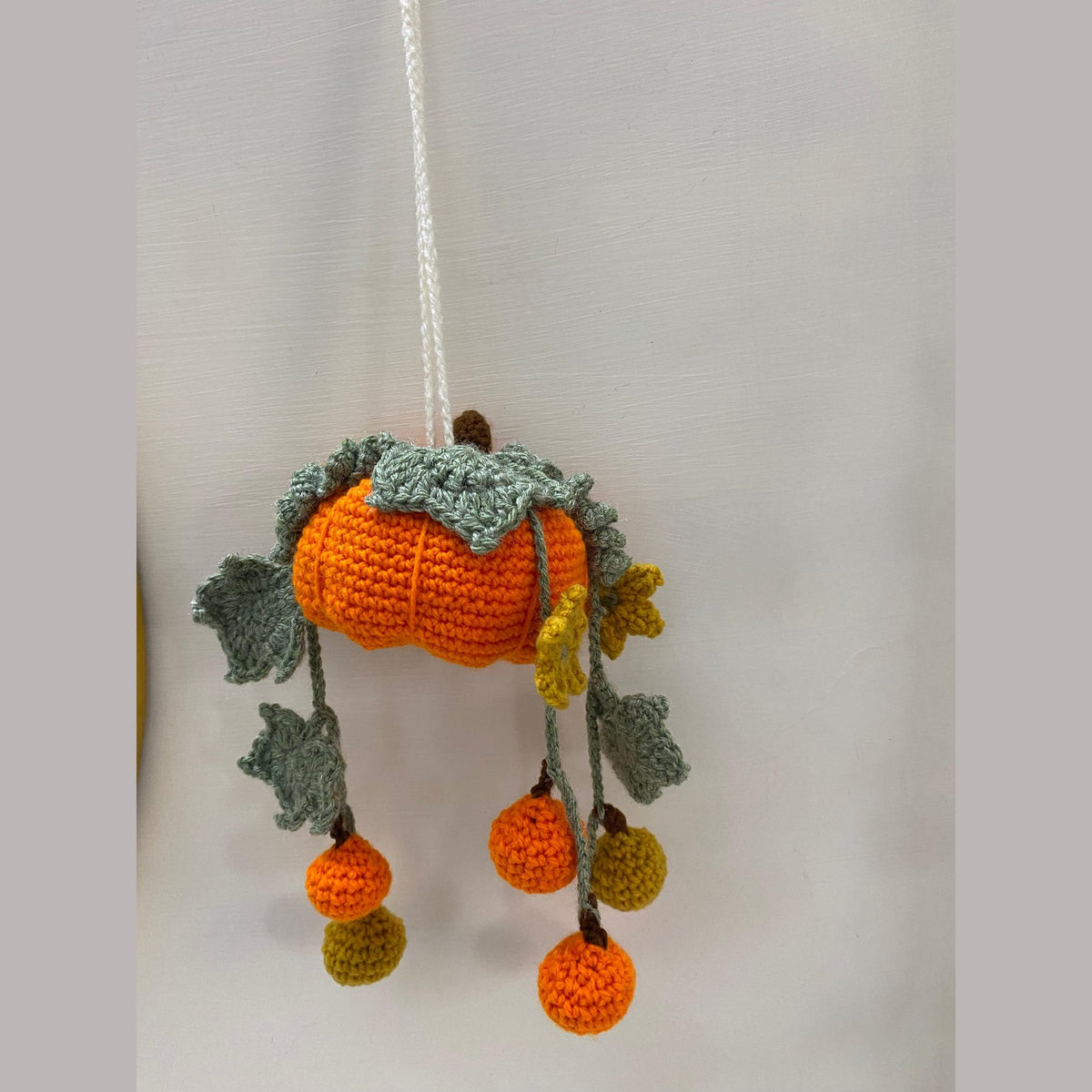 Handmade crochet pumpkin hanging with six small orange and olive pumpkins