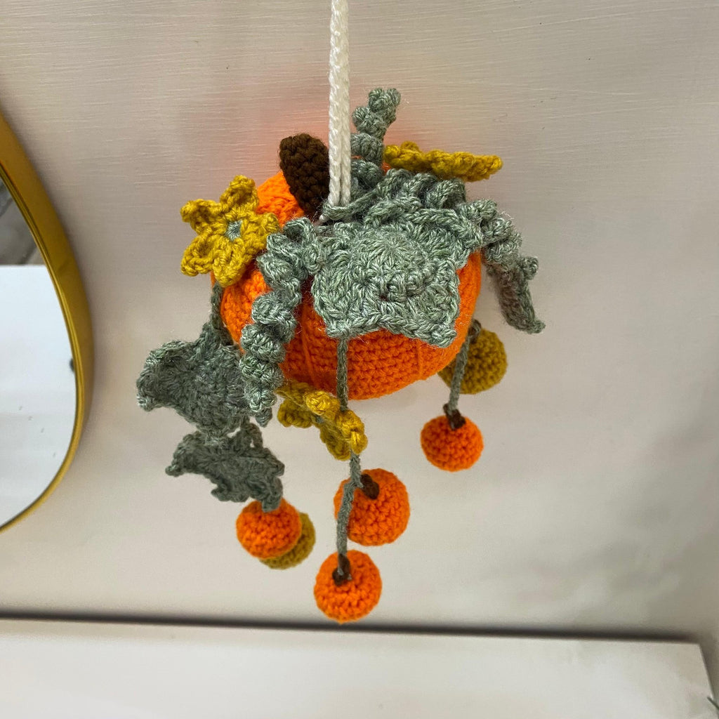 Close-up of the crochet pumpkin hanging showing the leaf collar and brown stem