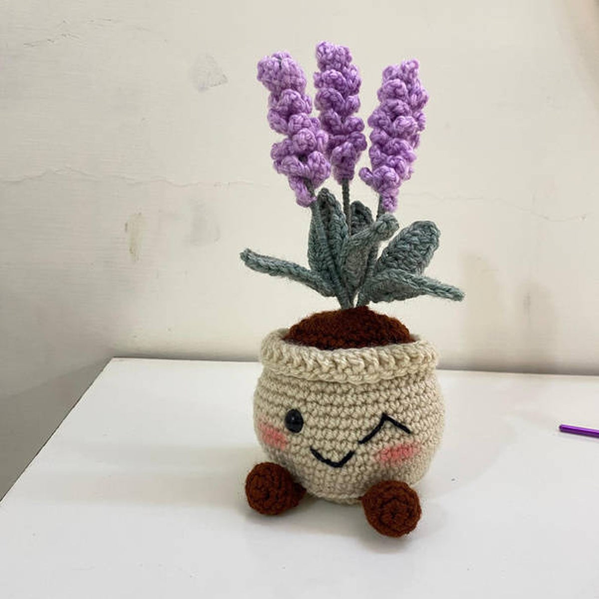 Crochet lavender plant pot with a smiling face, little legs and purple lavender stems