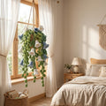 Crochet lily of the valley hanging plant with white and blue bells by a bedroom window