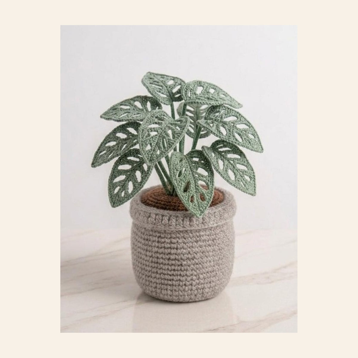 Crochet monstera plant with ten split leaves in a grey crochet pot