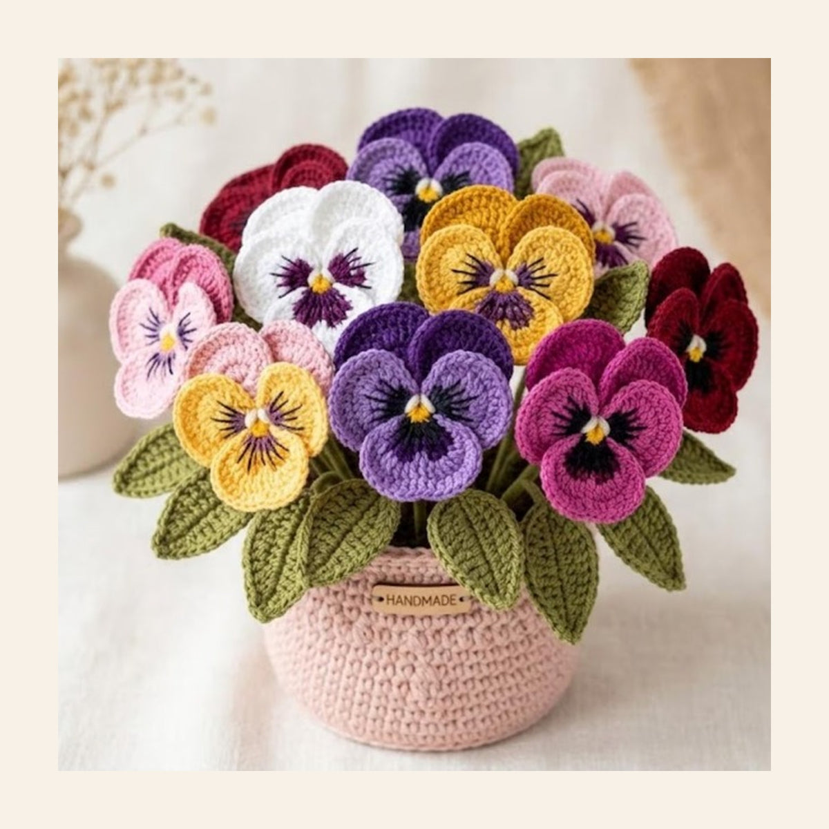 Crochet pansy flowers in purple and yellow in a pink crochet vase