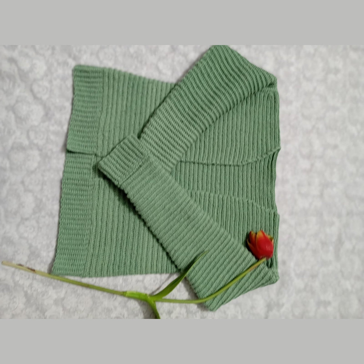 Green crochet rib stitch cardigan folded to show the ribbed sleeve and cuff