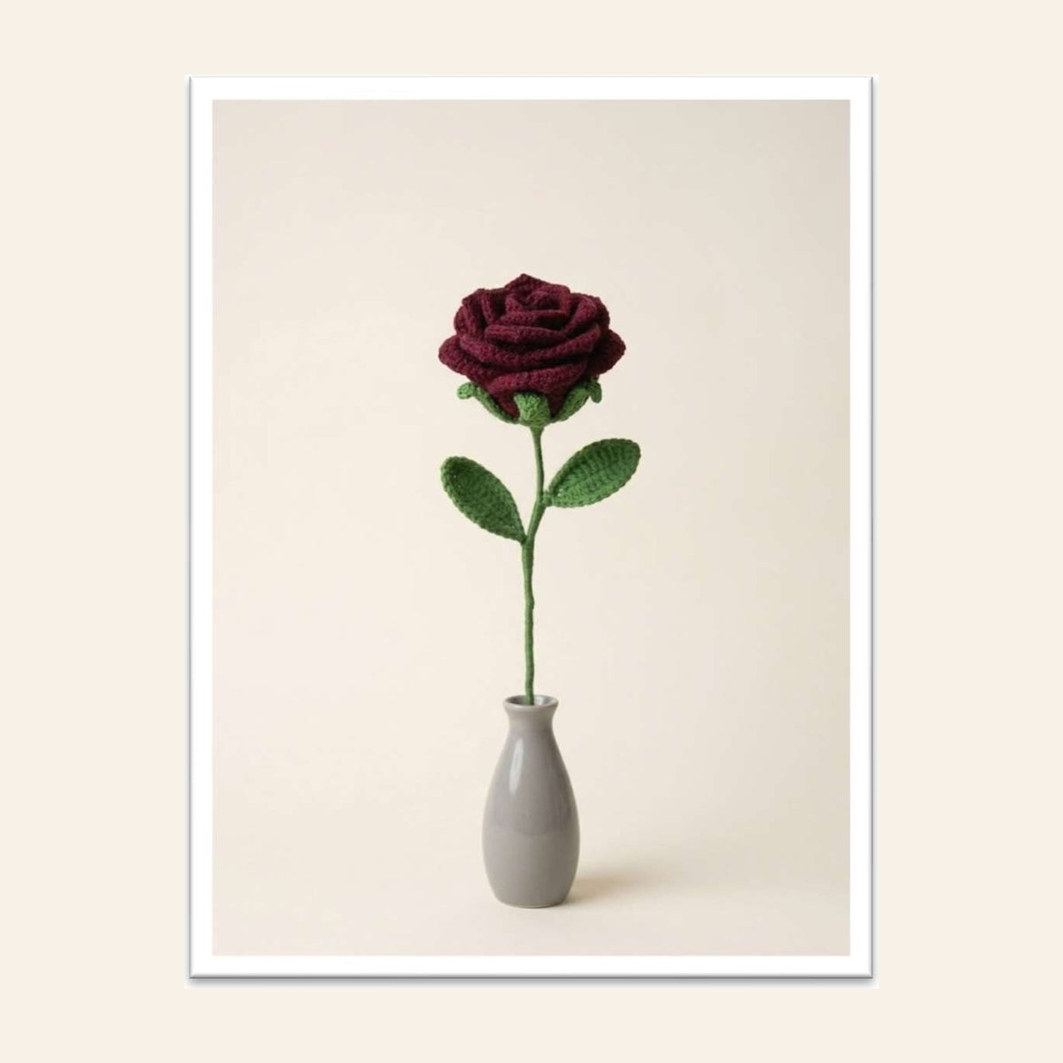 Deep red crochet rose with green leaves in a small grey vase